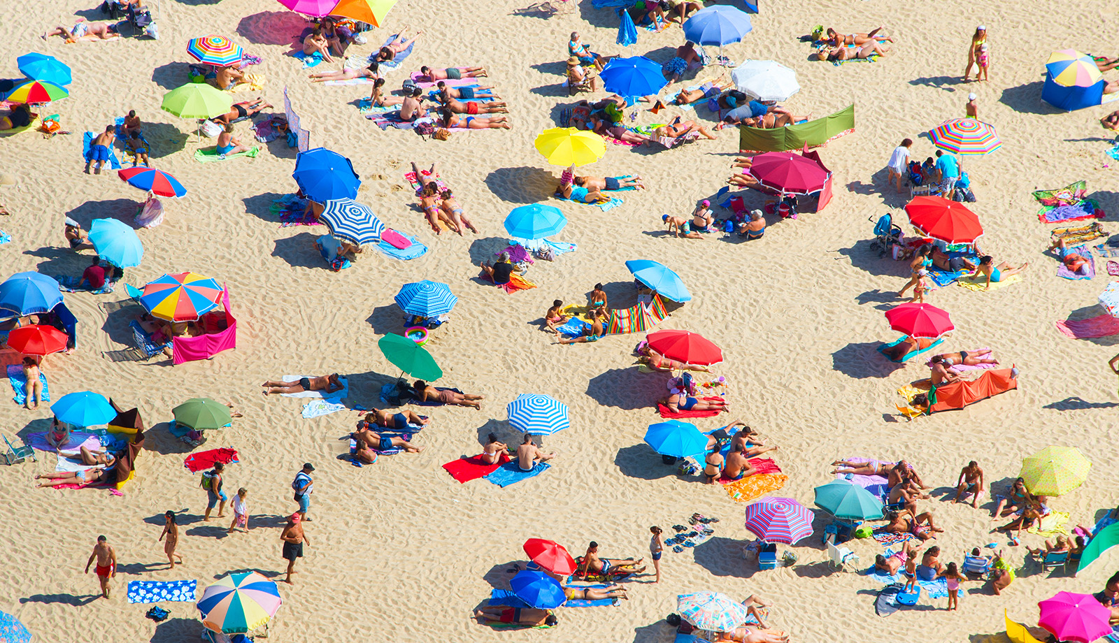 Druk zomers strand met gekleurde parasols Druk zomers strand met gekleurde parasols