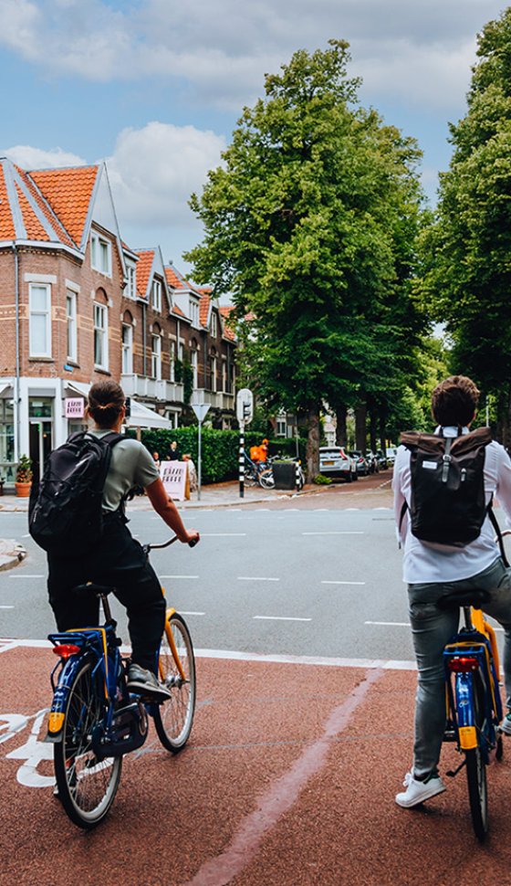 Bij een stads kruispunt wachten twee mensen op OV fietsen tot hun licht groen wordt.