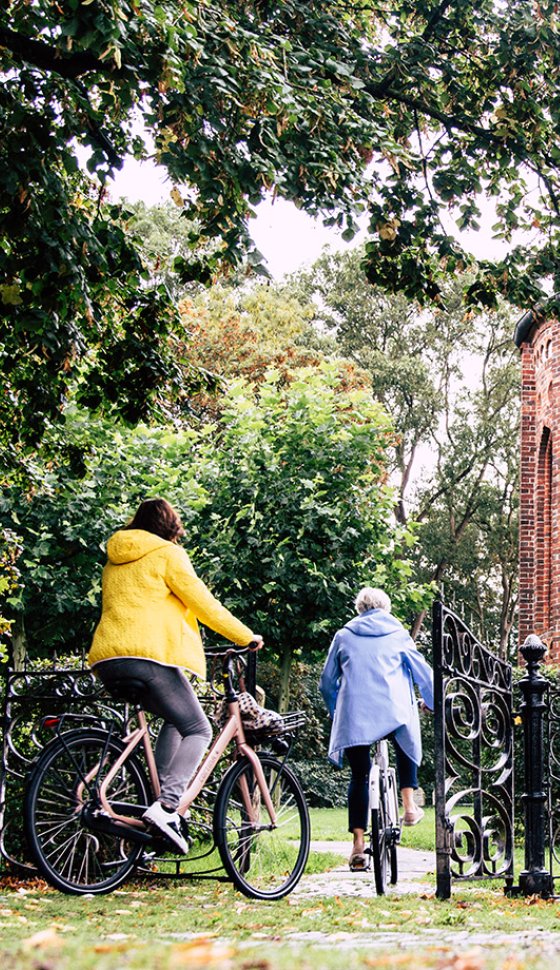 Twee vrouwen fietsen langs de historische Janskerk in Huizinge en ontdekken het Groningse landschap per fiets.