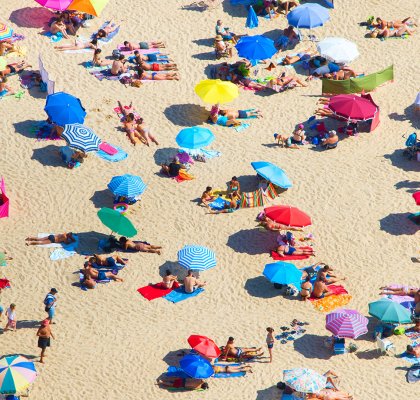 Druk zomers strand met gekleurde parasols