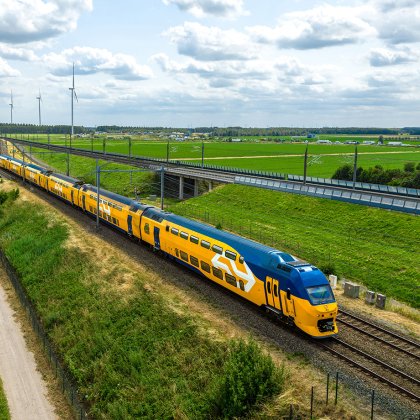 NS-trein rijdt door Nederlands landschap met windmolens