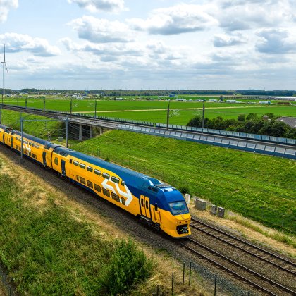NS-trein rijdt door Nederlands landschap met windmolens