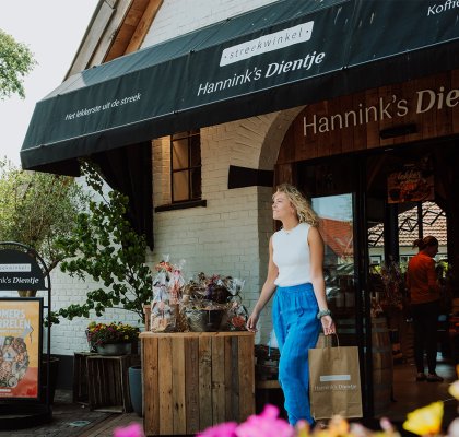 Vrouw doet boodschappen bij streekwinkel Hannink's Dientje in Enschede, waar lokaal ondernemerschap bijdraagt aan de waarde van toerisme