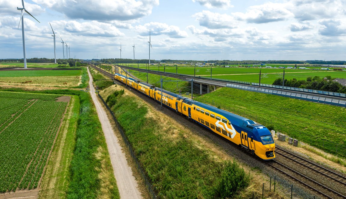 NS-trein rijdt door Nederlands landschap met windmolens